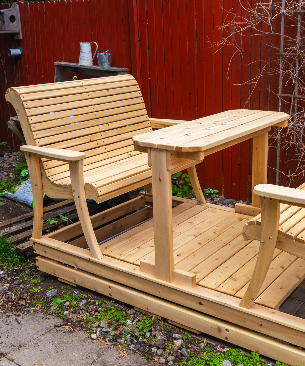 Open-air 4-seater wooden glider swing set configuration without a roof, featuring a built-in center table on a backyard patio.